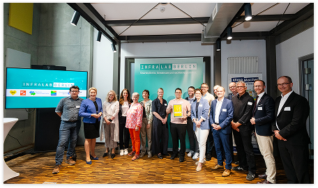 Gruppenfoto von Teilnehmenden einer InfraLab-Veranstaltung vor einer Präsentationswand